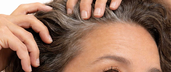 Close-up of a woman examining her scalp. Thinner hair and a more visible scalp are common early signs of hair loss.