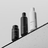 Hair Luxious Repair & Moisture shampoo and conditioner with the black For Him supplement jar on a wet surface