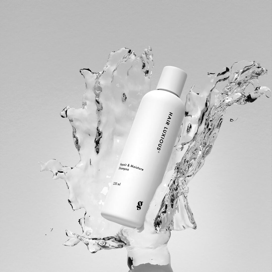 Hair Luxious Repair & Moisture Shampoo bottle surrounded by splashing water