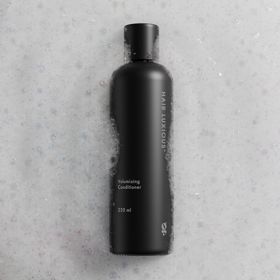 Hair Luxious Volumizing Conditioner bottle photographed flat on a stone surface