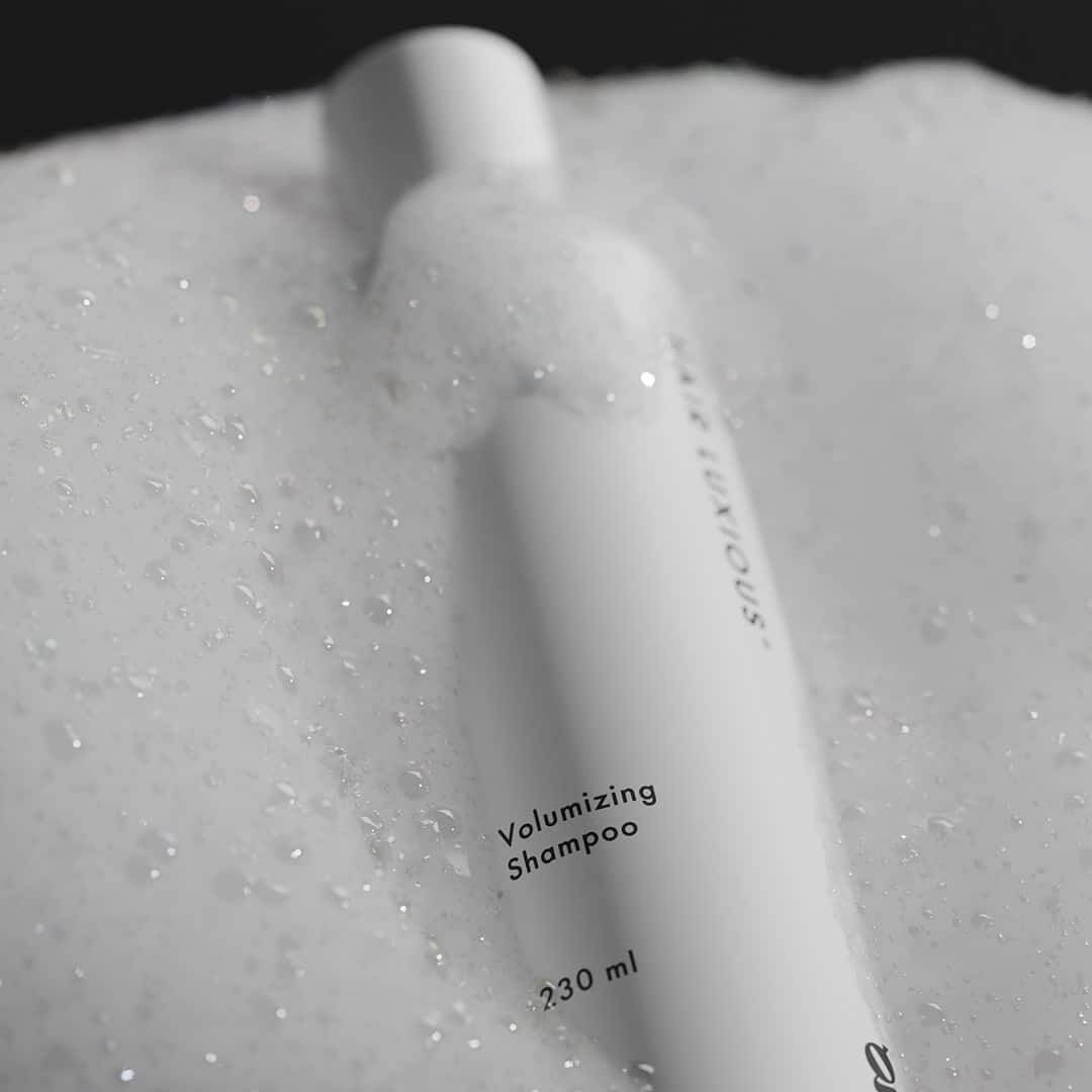 Hair Luxious Volumizing Shampoo bottle resting in foam