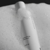 Hair Luxious Volumizing Shampoo bottle resting in foam